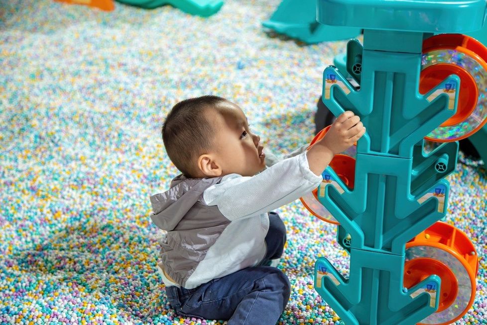 Toddler playing with construction toy in a soft-bead play area